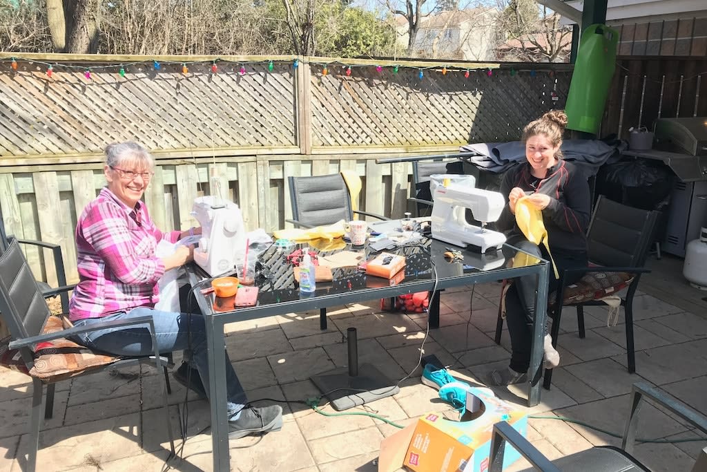 Two women sit at a table sewing.